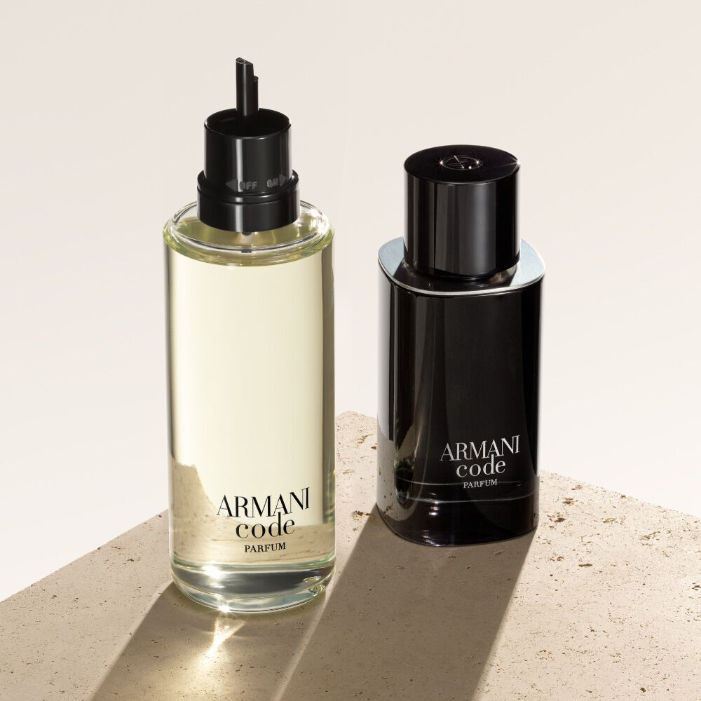 Twee flesjes Armani Code Parfum worden getoond tegen een getextureerde, beige achtergrond. Het linkerflesje is een navulling, met een lichtere, transparante uitstraling, terwijl het rechterflesje de klassieke, ondoorzichtige zwarte fles van de geur laat zien.