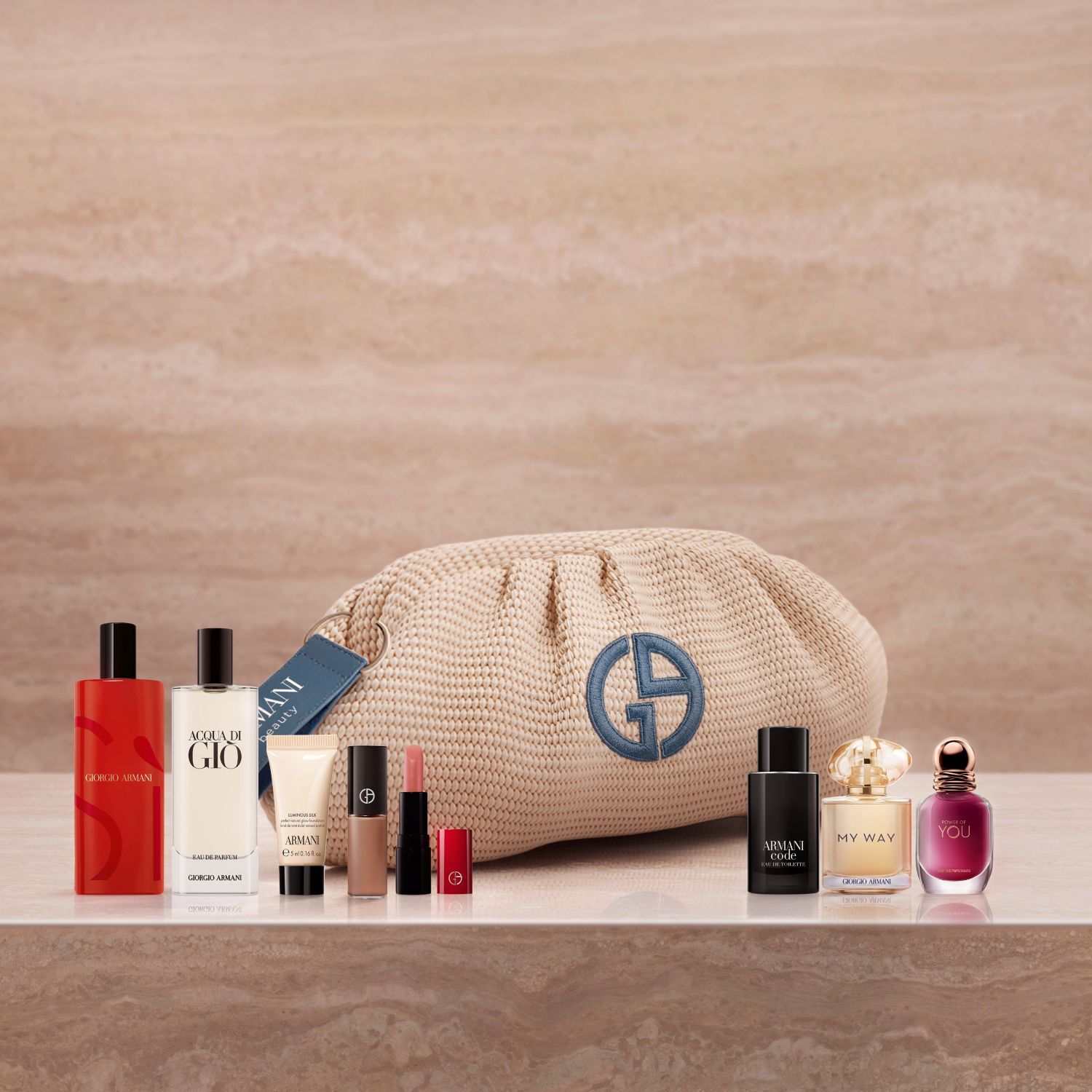 Een luxueuze selectie van Armani-iconen: Si, Acqua di Gio en My Way geuren, samen met Luminous Silk foundation en een lipstick. Gepresenteerd op marmer met een geweven beige tasje, viert deze collectie een verfijnde couture-schoonheid.
