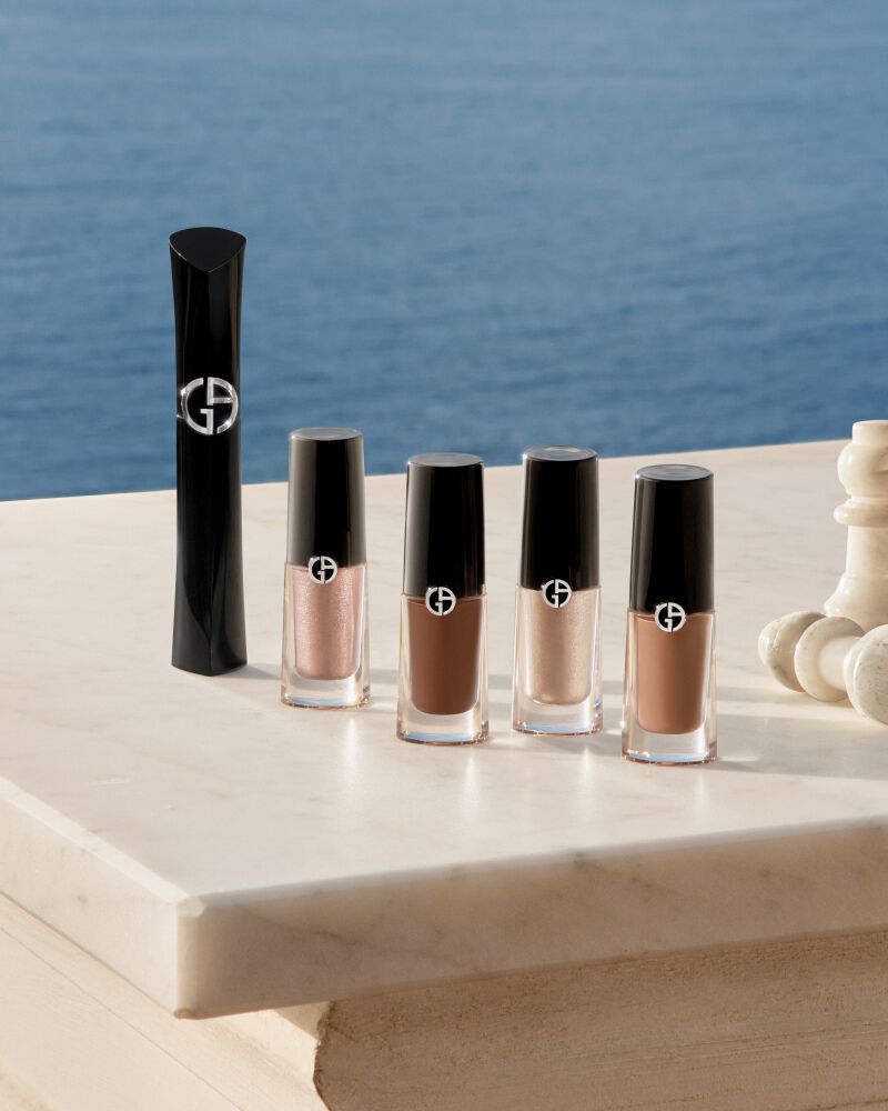 Een verfijnde selectie van Armani oog-iconen en schaakstukken op een marmeren terras aan zee. Dit beeld vangt de essentie van zonnige luxe en het vakmanschap van het Huis voor een stralende, natuurlijke blik.