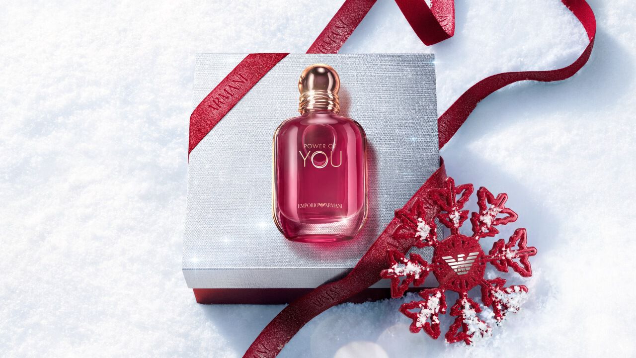 Ruby Power of You Eau de Parfum bottle with red Armani ribbon and jewelled snowflake on a snowy surface — Giorgio Armani women's fragrance, holiday gift set visual.