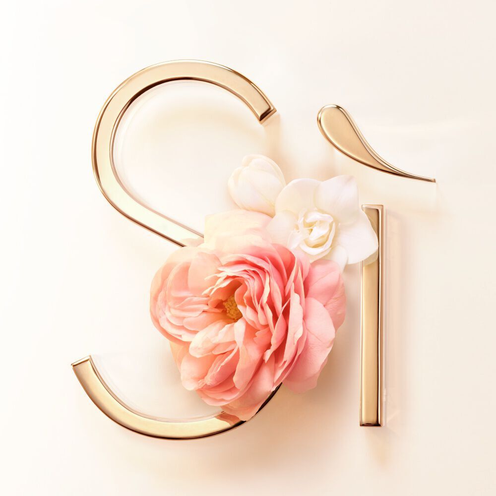 Pink rose de mai bloom against the gold Si signature on a blush background — rose de mai and freesia heart notes of Si Eau de Parfum by Giorgio Armani.