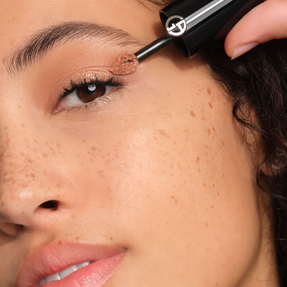 Close-up of Giorgio Armani Eye Tint shade 40S applied as a precise liquid liner on a model, with an eyeliner brush visible against skin.