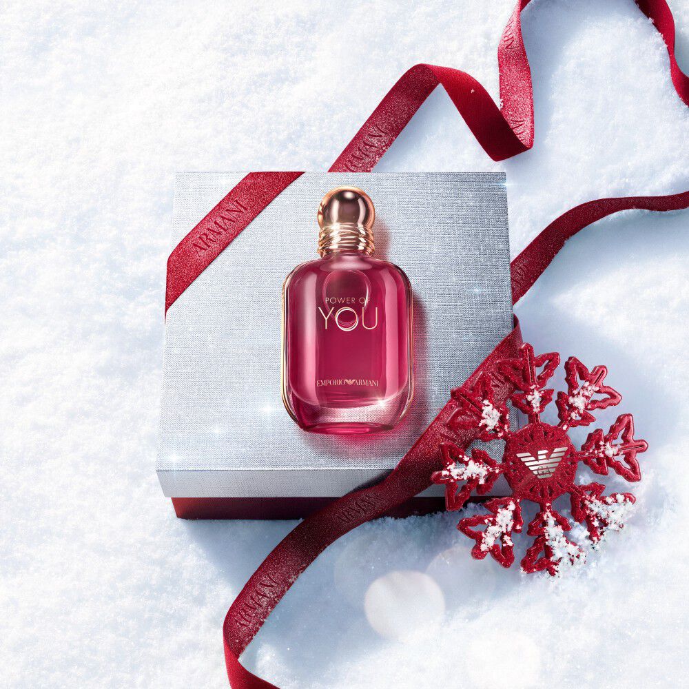 Ruby Power of You Eau de Parfum bottle with red Armani ribbon and jewelled snowflake on a snowy surface — Giorgio Armani women's fragrance, holiday gift set visual.