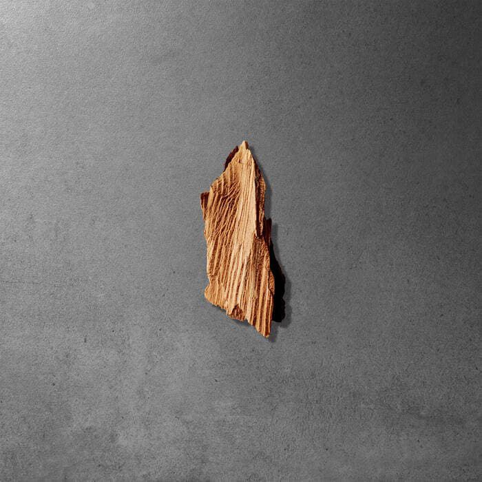 A small, irregular piece of wood displayed against a dark grey background.