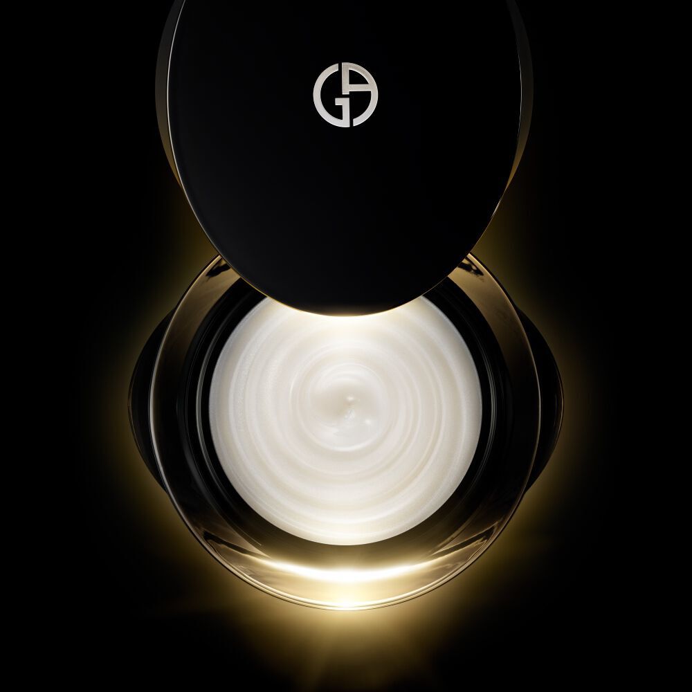 Een pot Crema Nera Supreme Reviving Cream is open, waardoor de rijke, wervelende witte creme zichtbaar is.