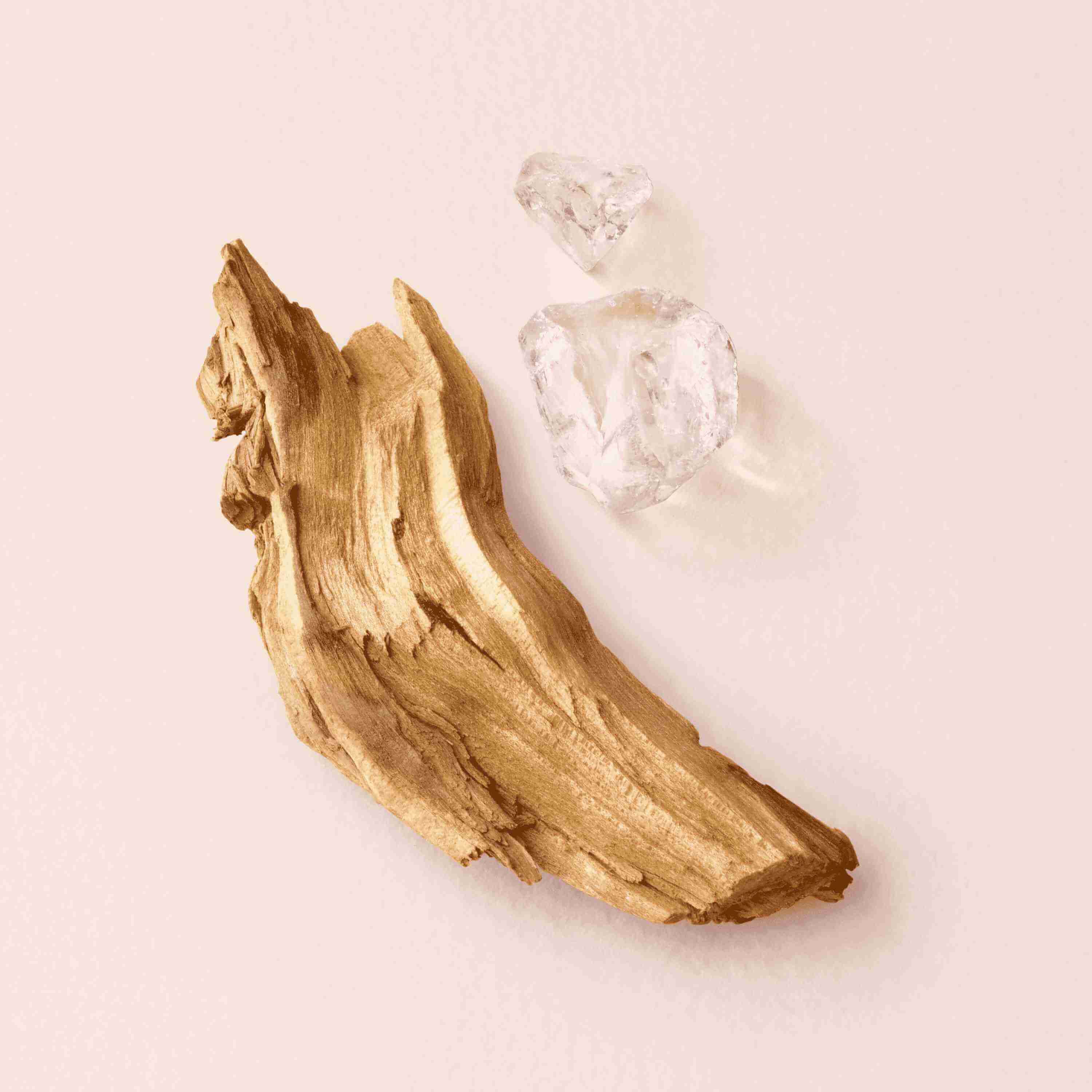 A piece of polished wood alongside two clear crystalline hearts on a soft pink background.