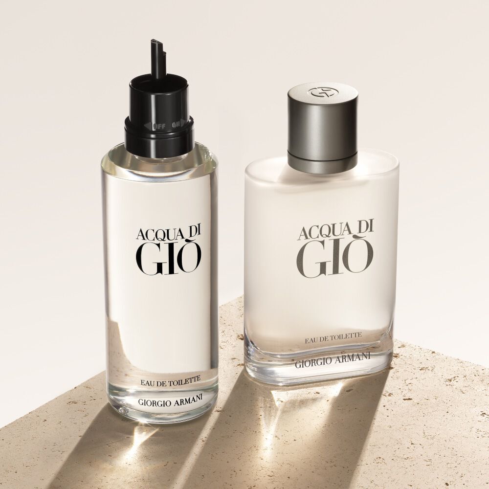 Twee flesjes Acqua di Gio Eau de Toilette, de navulling links, worden gepresenteerd op een beige, getextureerde achtergrond.