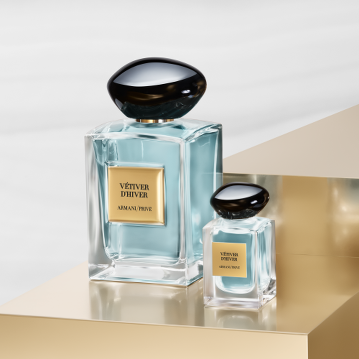 Armani/Prive: een iconische flacon en zijn elegante miniatuur die een lichtgroene essence onthullen. Geplaatst op een gouden voetstuk vieren ze de serene balans van thee en de ambachtelijke luxe van het Huis.
