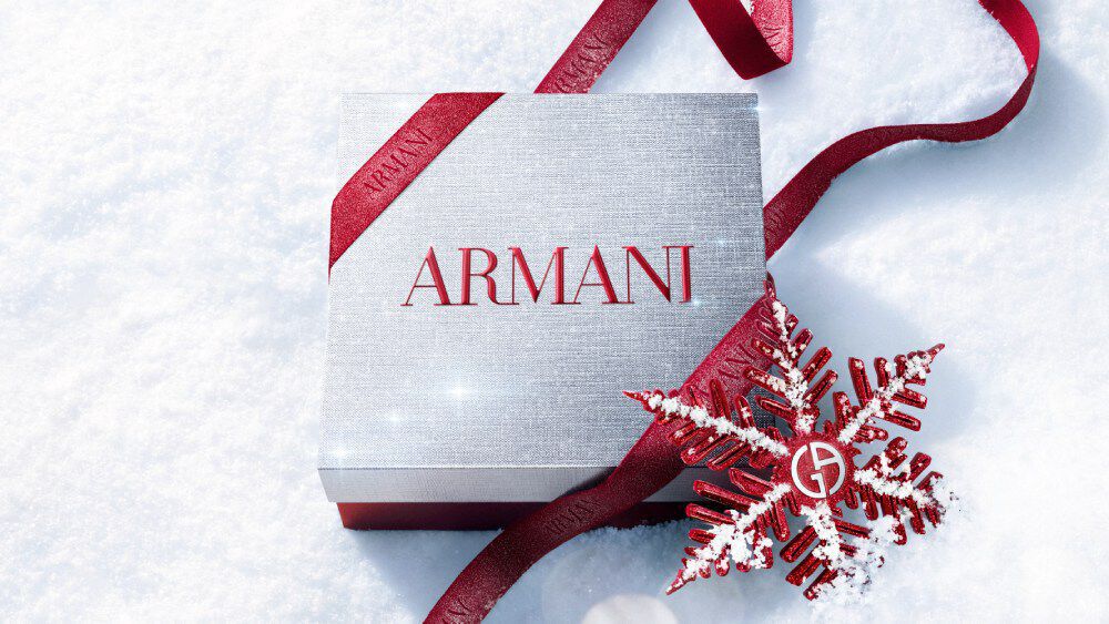 Armani beauty Holiday 2026 white gift box tied with a red ribbon and snowflake decoration on a snowy surface