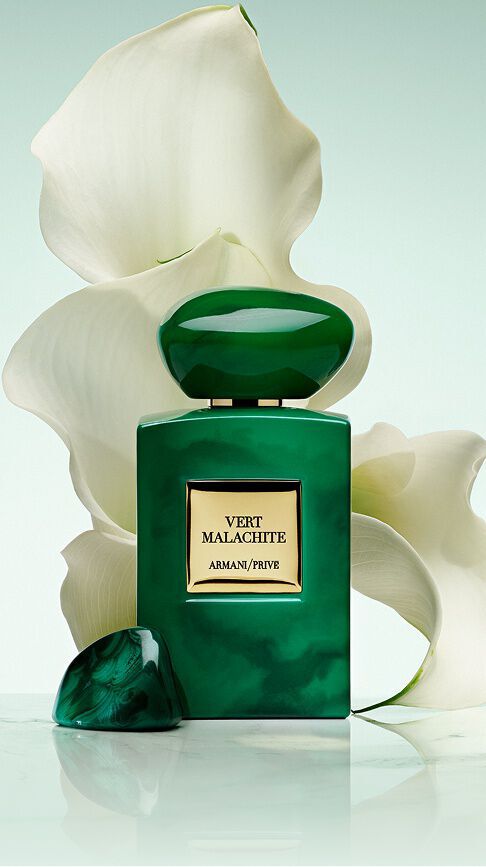 Armani/Prive Vert Malachite: een levendige smaragdgroene flacon met een steenachtige dop, geplaatst voor stralend witte lelies, die de frisse pracht van een Russische tuin in een sereen licht vangt.