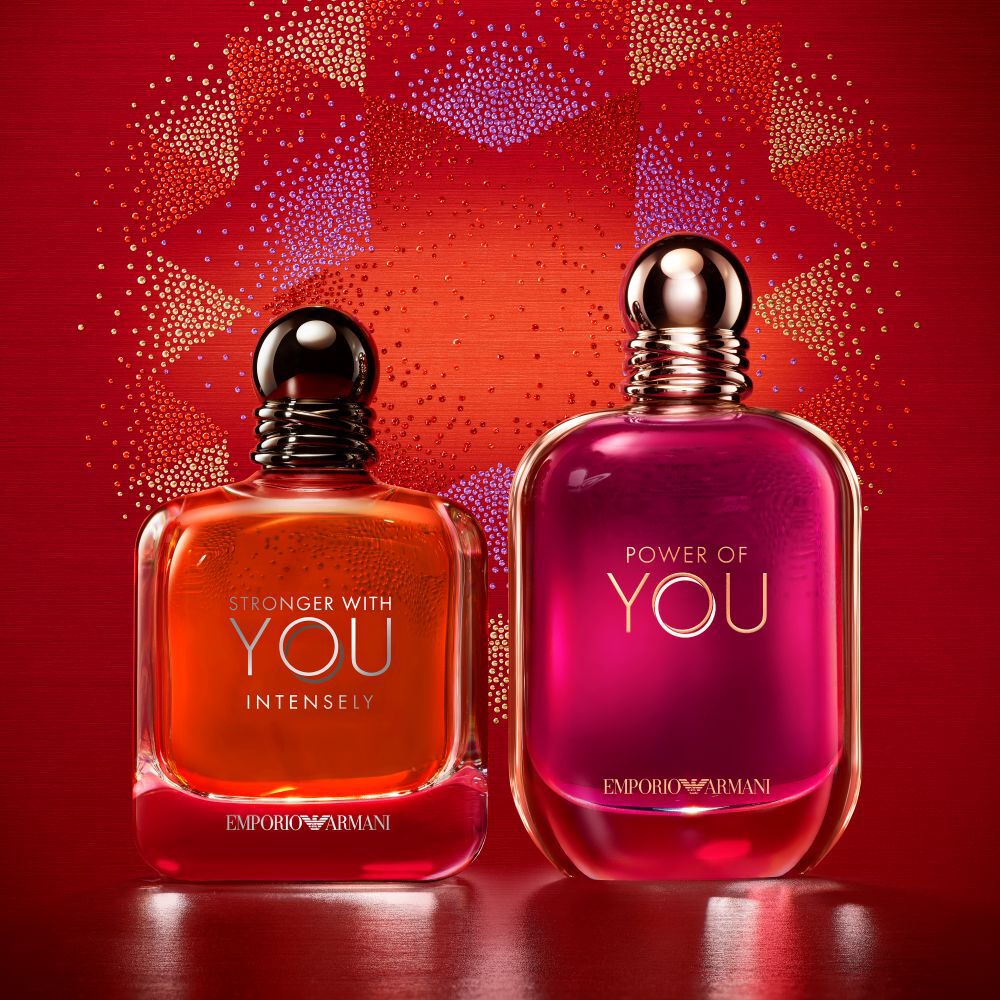 Twee Emporio Armani-geuren, Stronger With You Intensely en Power of You, tegen een feestelijke rode achtergrond.​