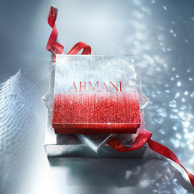 Glinsterende Armani geschenkdoos met rood lint op een sprankelende ondergrond.