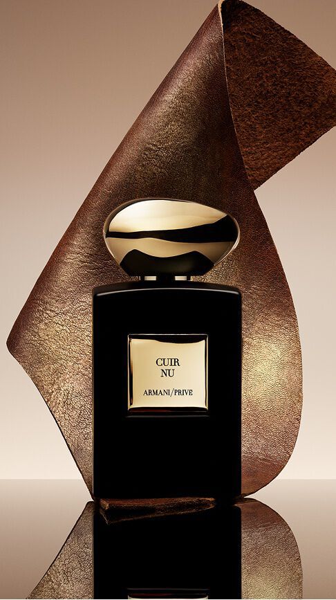 Armani/Prive Cuir Nu: een elegante zwarte flacon met een gouden dop, gedrapeerd met een getextureerd lederen lint, die de sensualiteit van de blote huid en de verfijning van een houtachtige geur belichaamt.