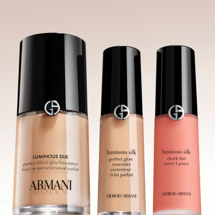 De iconische Luminous Silk-collectie: Foundation, Concealer en Verhelderende Blusher. Elegante flacons met zwarte doppen en zilveren Giorgio Armani-logo's tegen een zachte achtergrond belichamen de legendarische, gewichtloze glow van Armani Beauty.