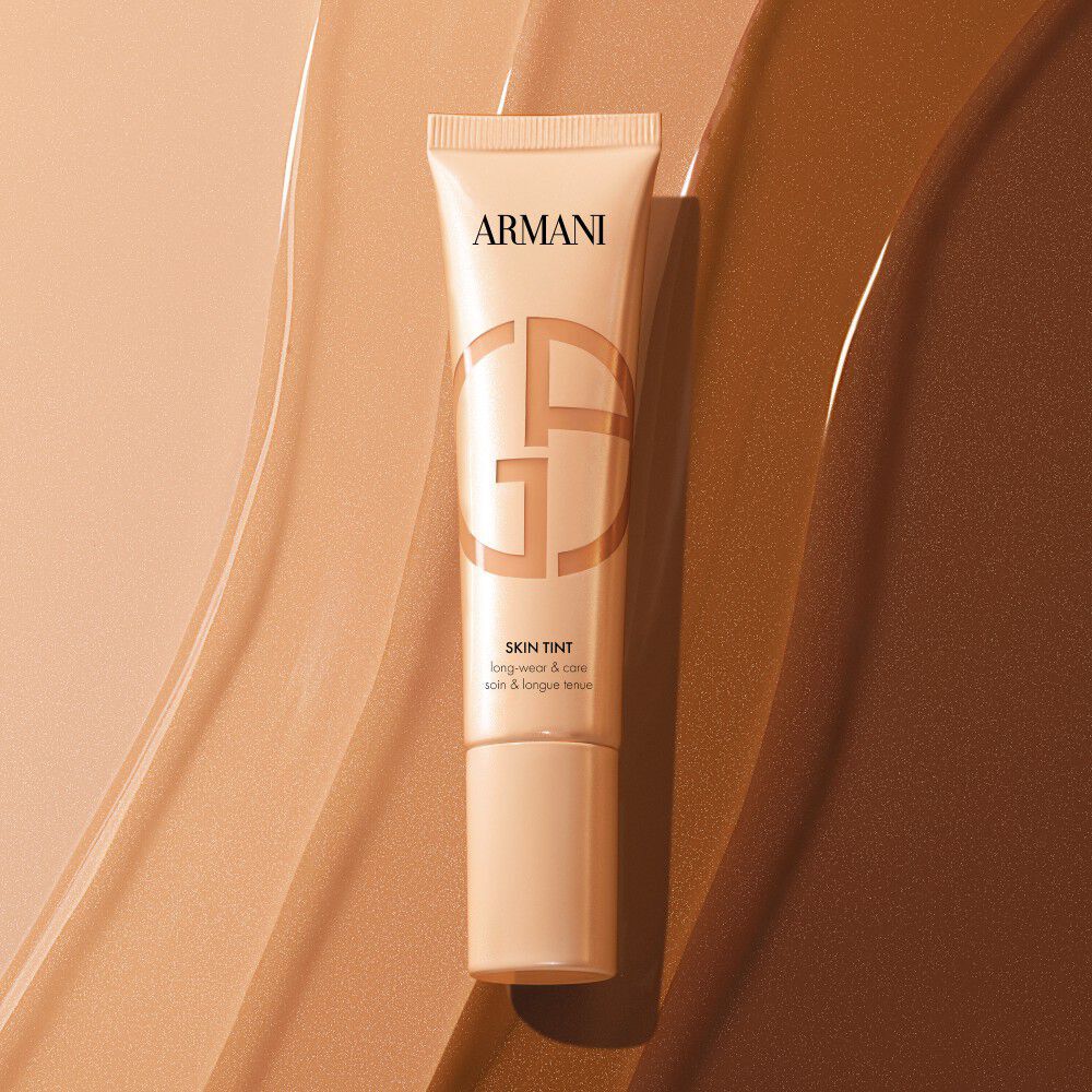 Armani Skin Tint tube op vloeibare foundation swatches in verschillende tinten.