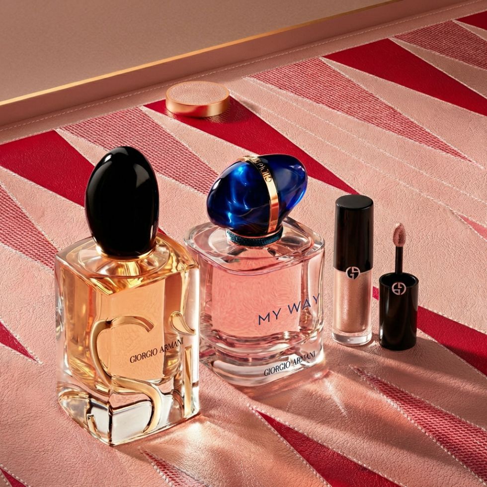 Een luxueuze selectie Armani-iconen: de geuren Si en My Way staan naast een essentieel make-upitem. De geometrische roze en rode achtergrond, geinspireerd op couture, weerspiegelt tijdloze schoonheid en uniek vakmanschap van het huis Armani.