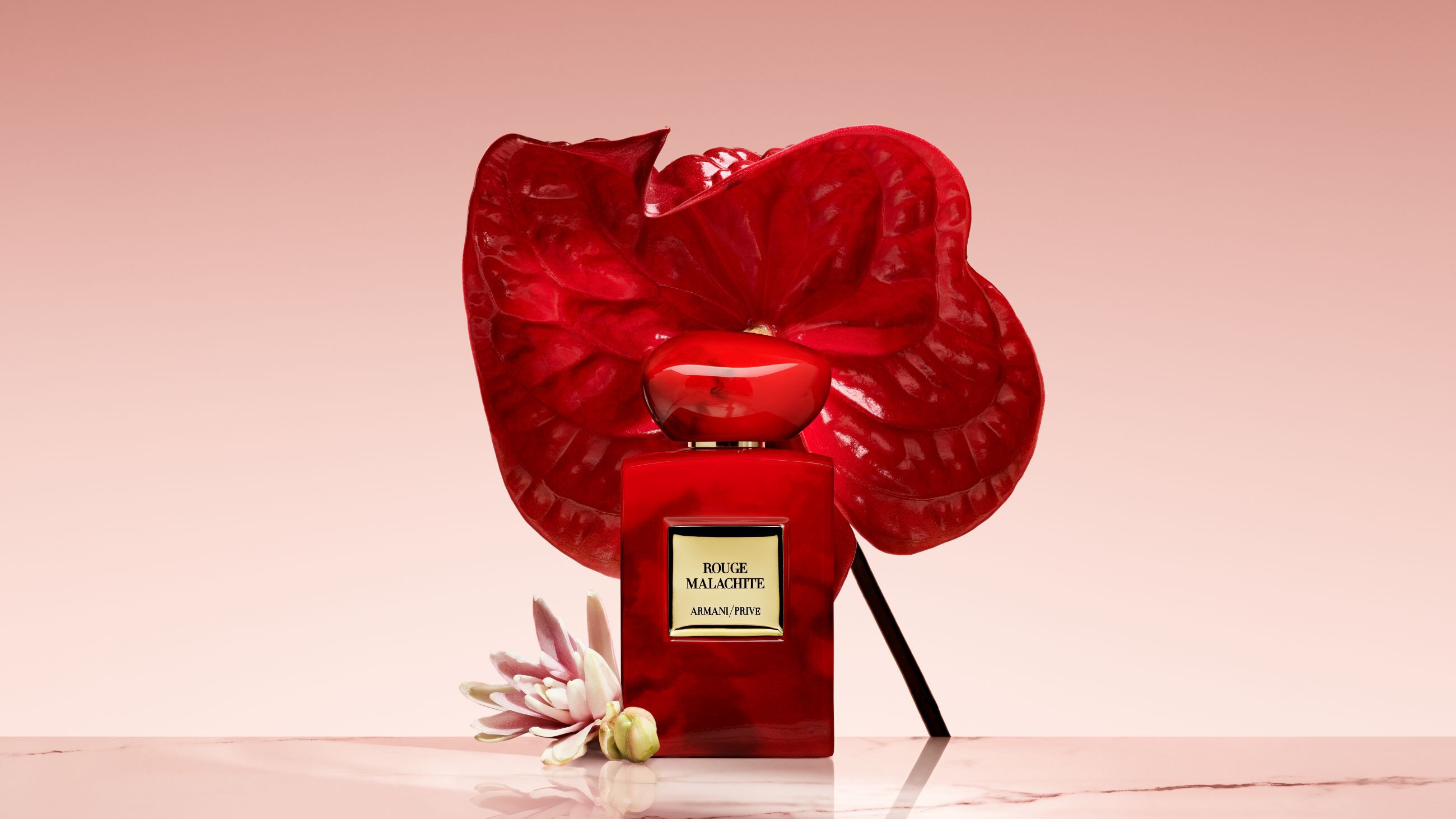 Armani/Prive Rouge Malachite parfumflacon voor een grote, felrode bloem.