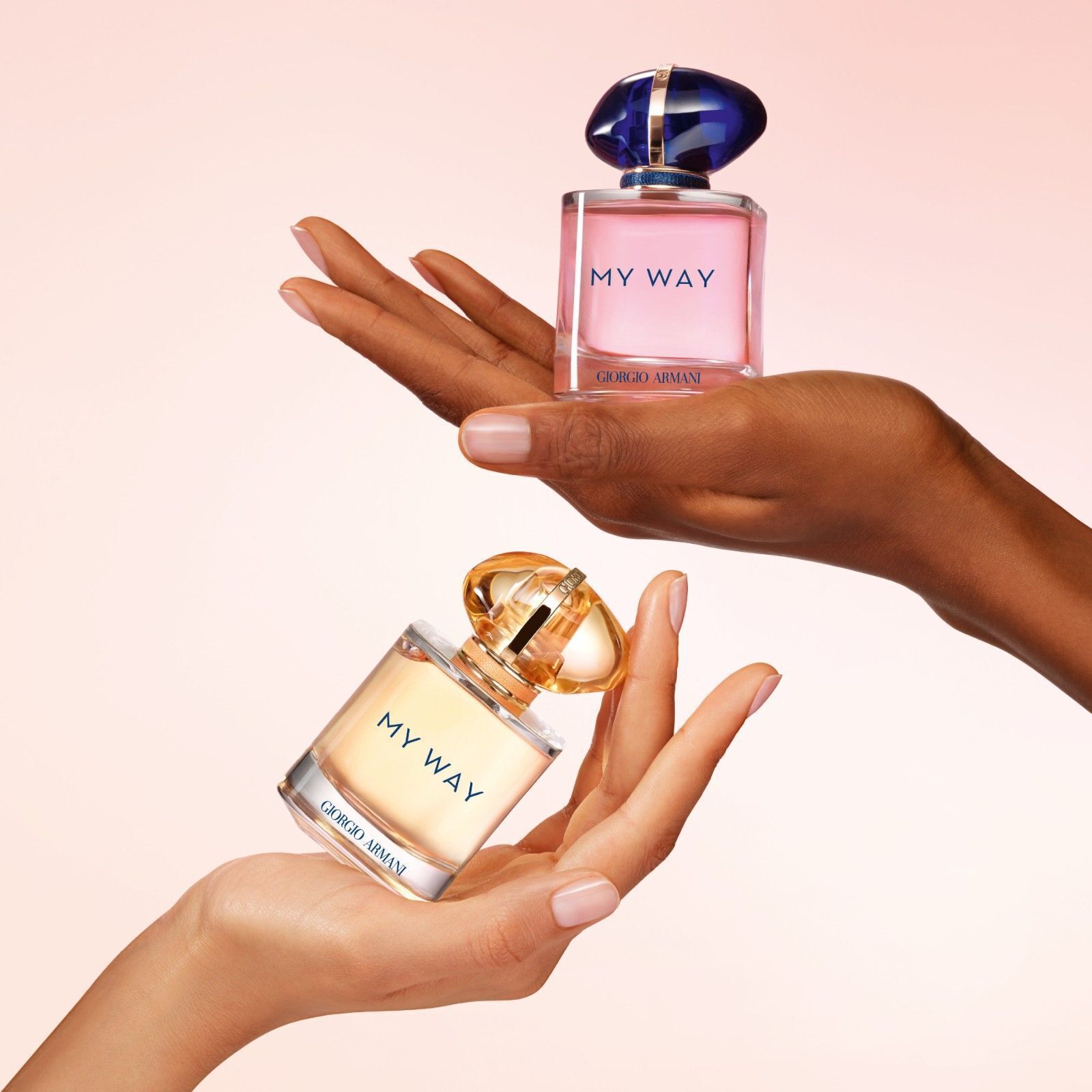 Twee handen houden Flessen van Giorgio Armani My Way Sunny Vanilla en My Way Eau de Parfum in verschillende kleuren vast, wat diversiteit en het scala aan geuren benadrukt.