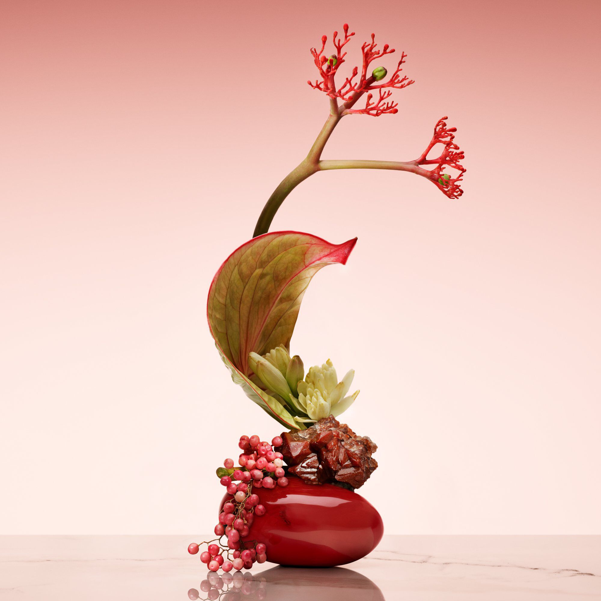 Armani/Prive Rouge Malachite: artistiek ikebana-arrangement met rode bloemen en groene accenten, die vakmanschap van hoog niveau laat zien.