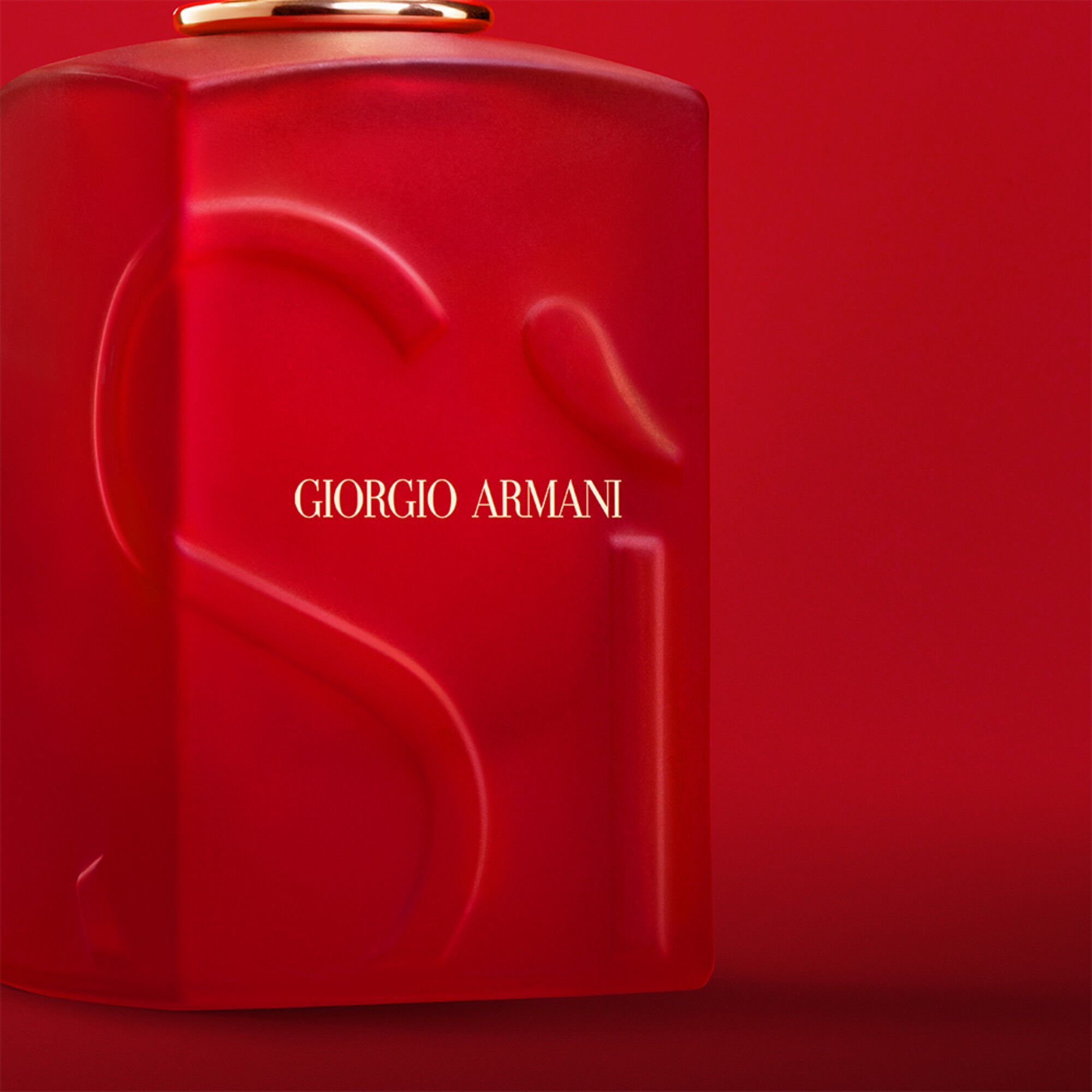 Giorgio Armani Si Passione Red Bloom parfum dichtbij op de fles op een rode achtergrond.