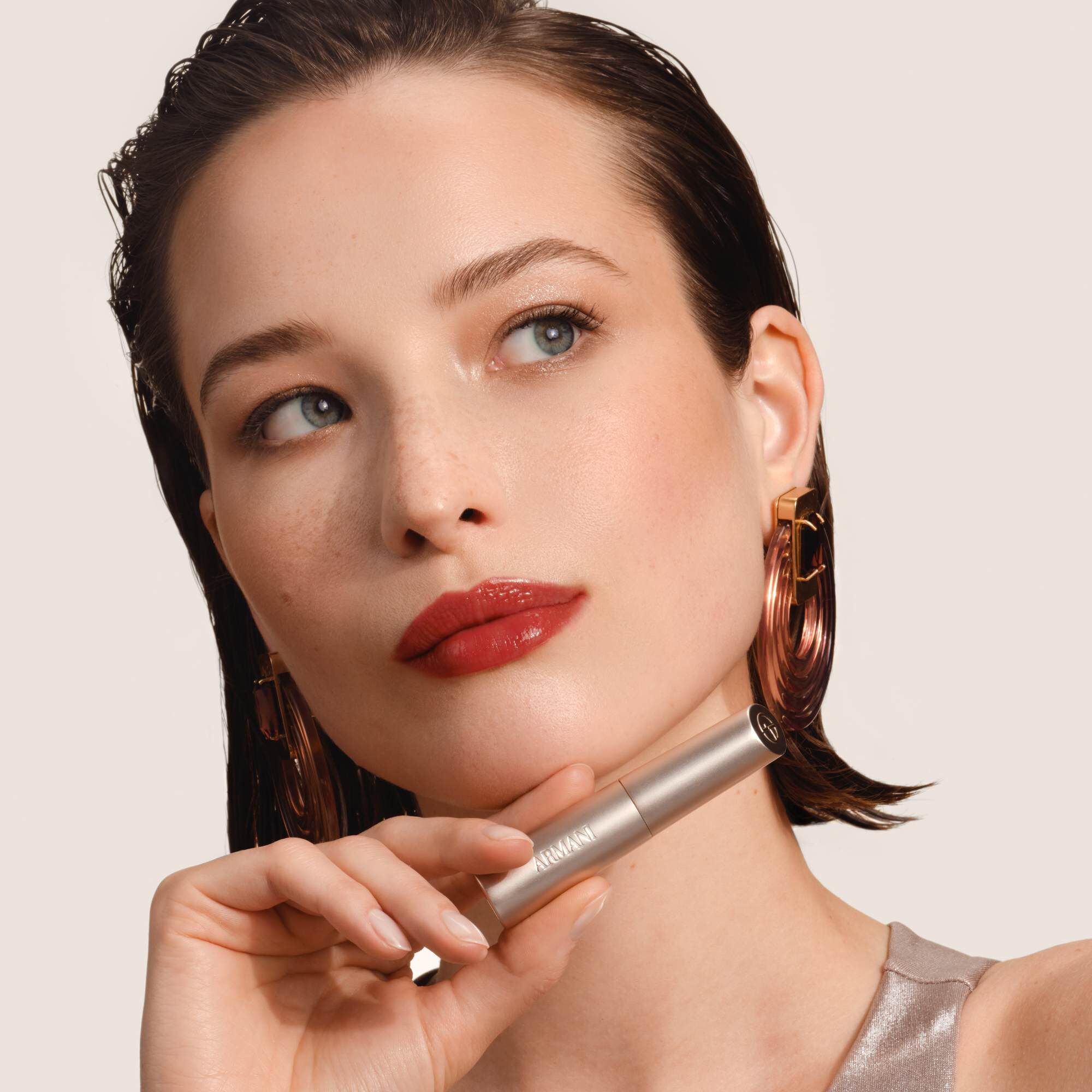 Armani Prisma Flash lippenstift aangebracht, met de nadruk op het strakke metallic ontwerp en de romige textuur van het product.