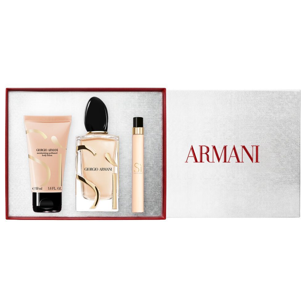 Si Eau de Parfum 100ml, reismaat 10ml en 50ml geparfumeerde bodylotion met goudtinten flessen naast een open witte Armani cadeaudoos met rood lint — dames bloemengeur-cadeauset met witte achtergrond.
