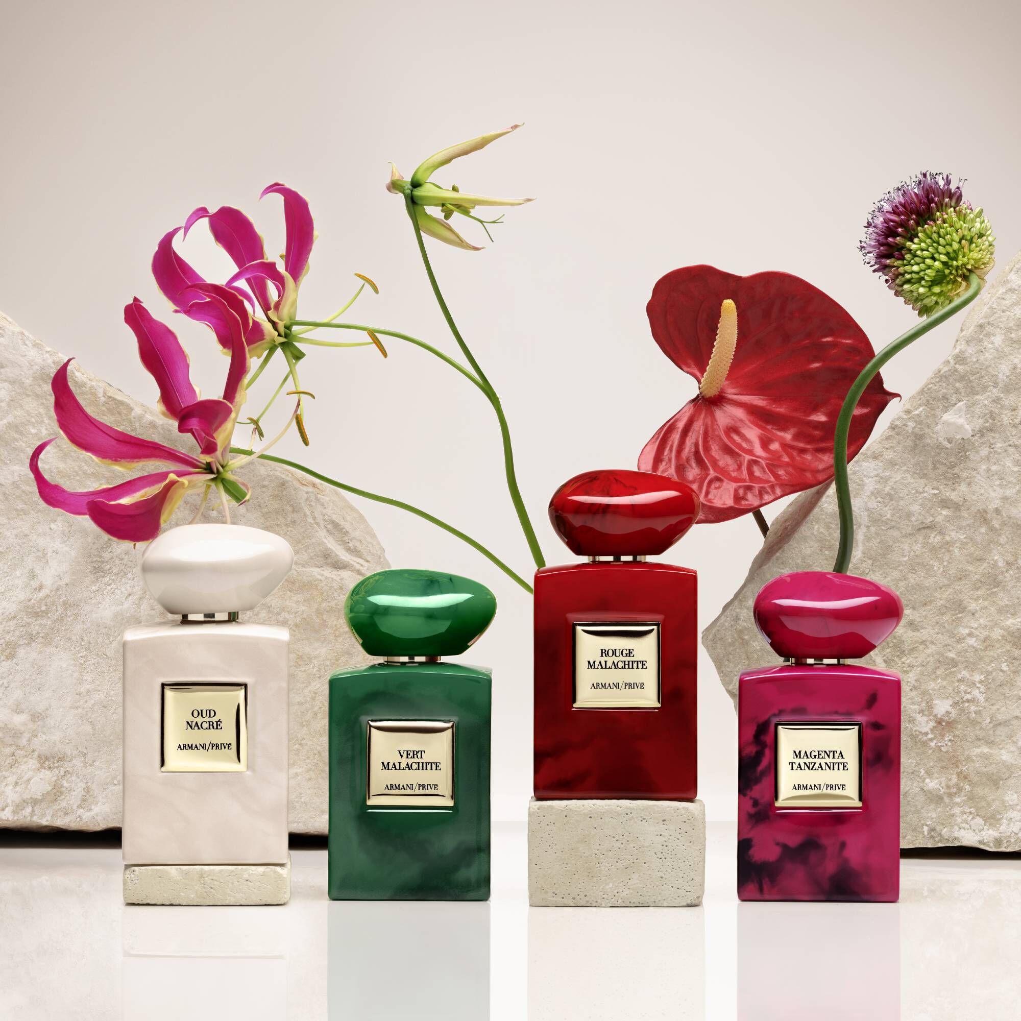 Collectie Armani Prive parfumflessen in verschillende kleuren met bloemaccenten.