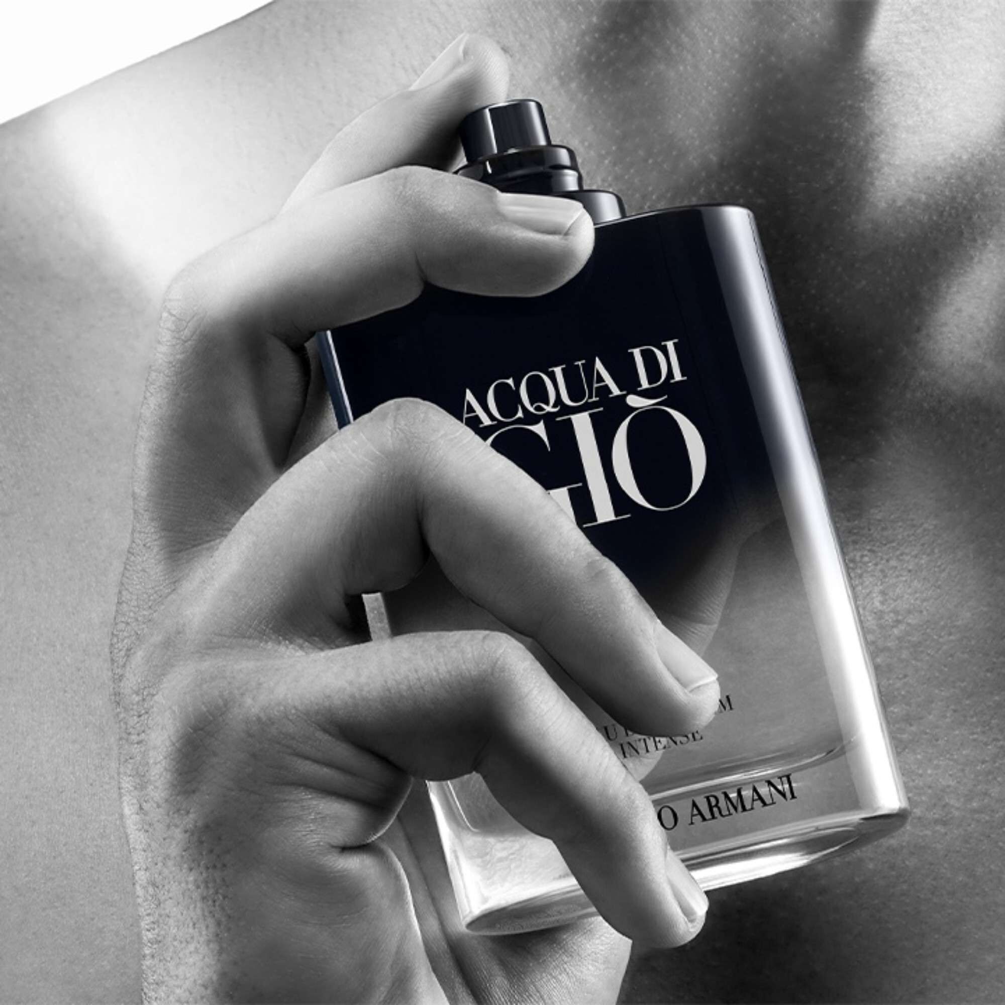 Hand Giorgio Armani Acqua Di Gio Eau de Parfum Intense flesje vasthoudend, de geur op de huid spuitend.