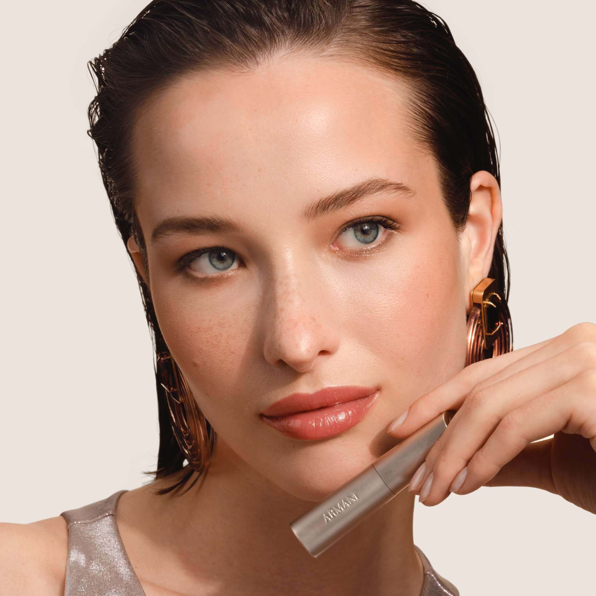 Armani Prisma Flash lippenstift aangebracht, met de nadruk op het strakke metallic ontwerp en de romige textuur van het product.