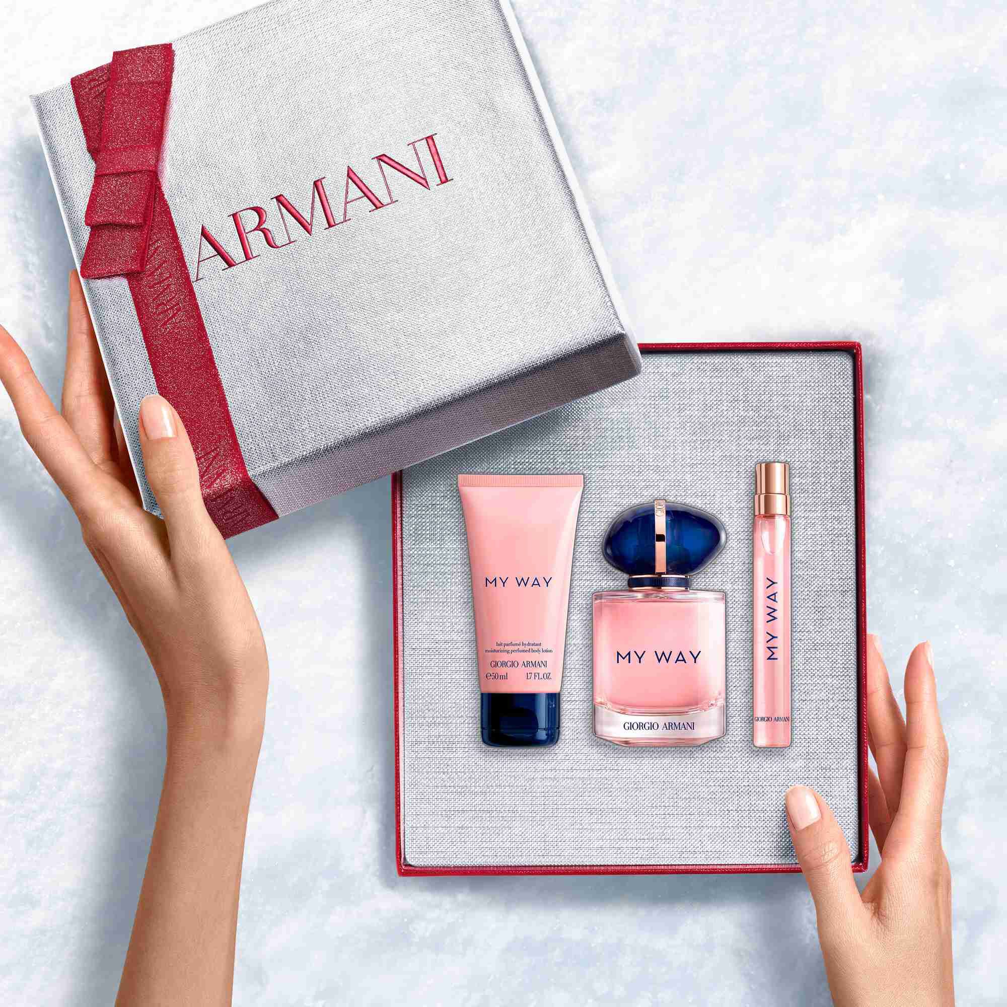 Hands onthullen een witte Armani-cadeaudoos met robijnlint met My My Way Eau de Parfum 90ml geur, een fles van 10ml en een 50ml geparfumeerde bodylotion — een verfijnde bloemengeurset voor vrouwen.