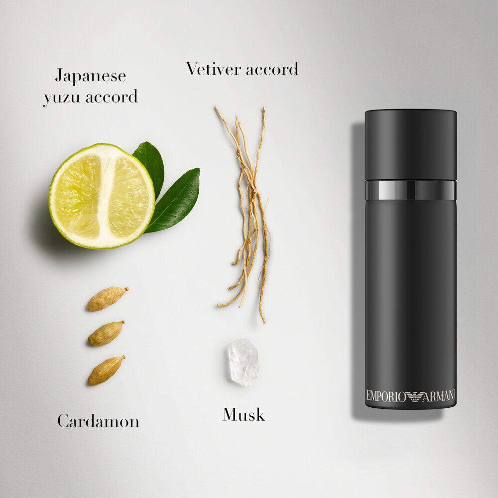Een flat lay-compositie voor de Emporio Armani-geur, met een 100ml zwarte fles samen met Japanse yuzu, vetiver, kardemom en muskusingredienten, op een witte achtergrond.