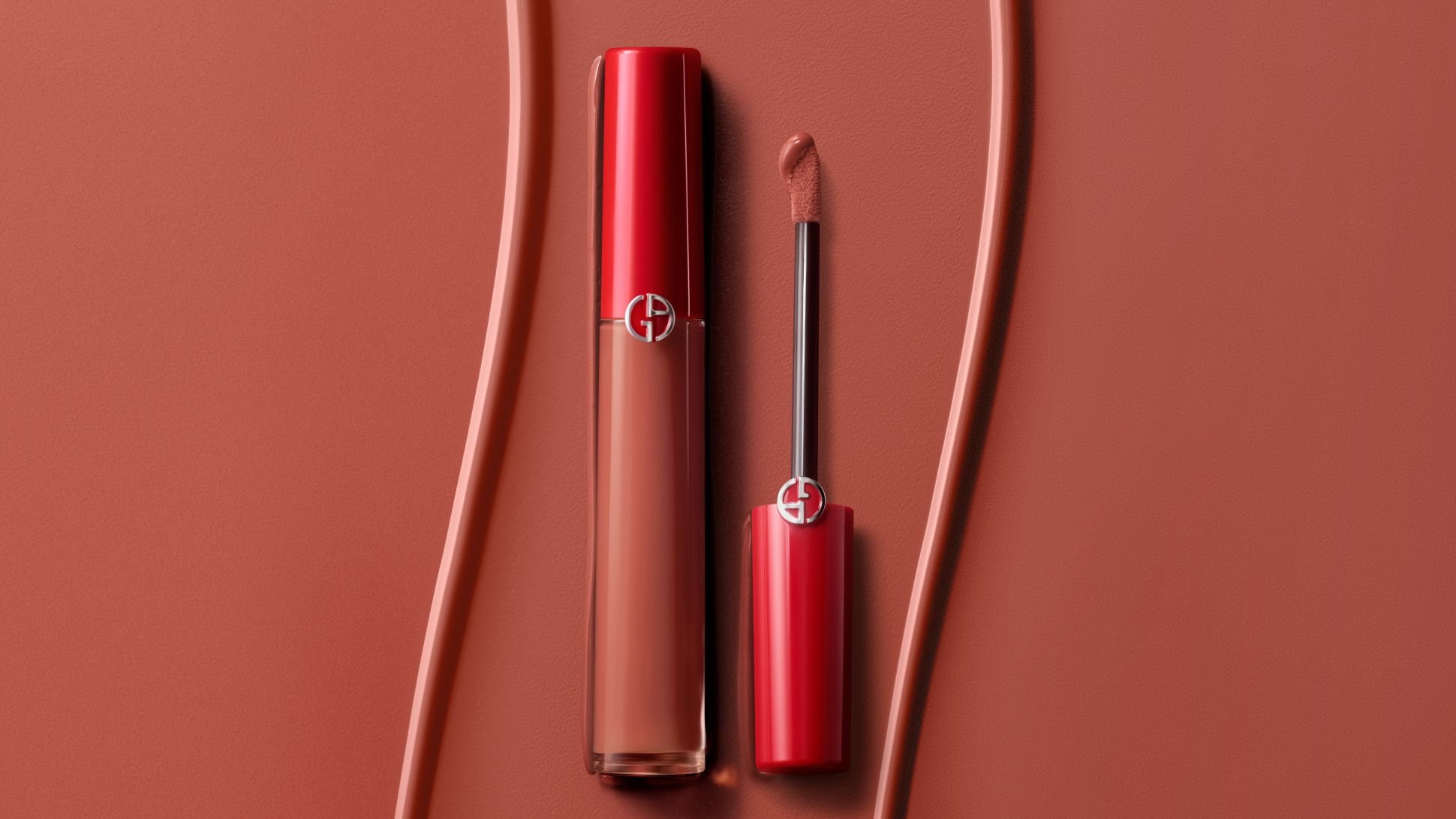 Vloeibare lippenstift van Giorgio Armani met applicator op een getextureerde terracotta achtergrond.