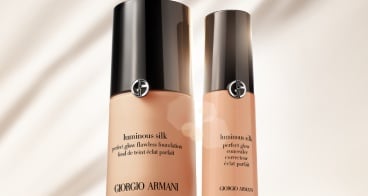 Twee flessen Giorgio Armani Luminous Silk Foundation op een rode achtergrond, gericht op de luxe uitstraling van het product.